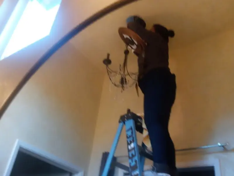 Electrician installing a chandelier in a Enoch residence